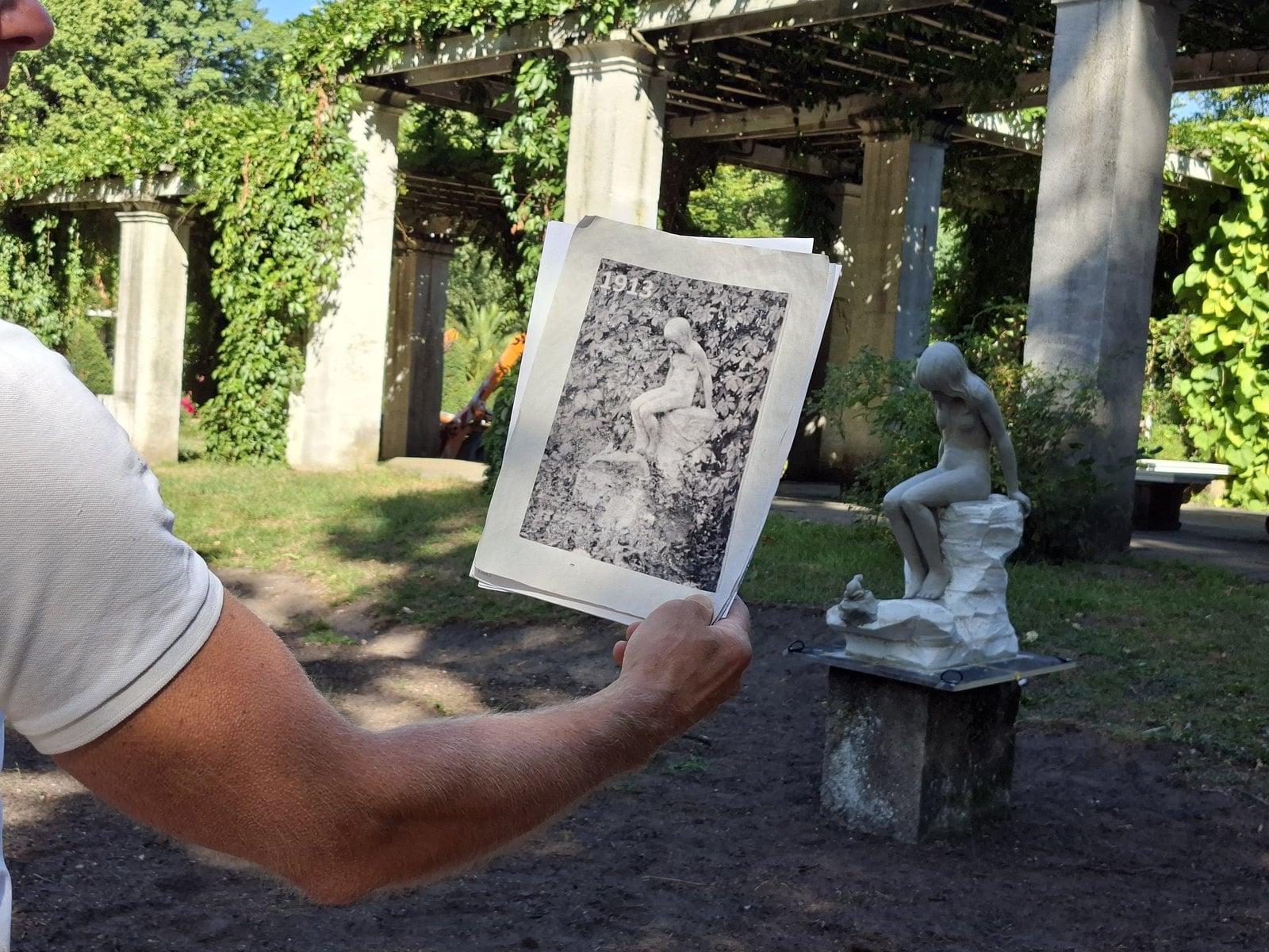 Historisches Foto wird neben das Tonmodell der sitzenden Wassernixe im Pergolenhof gehalten