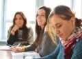 Drei Frauen sitzen an einem Tisch in einem hellen Raum und arbeiten mit Unterlagen