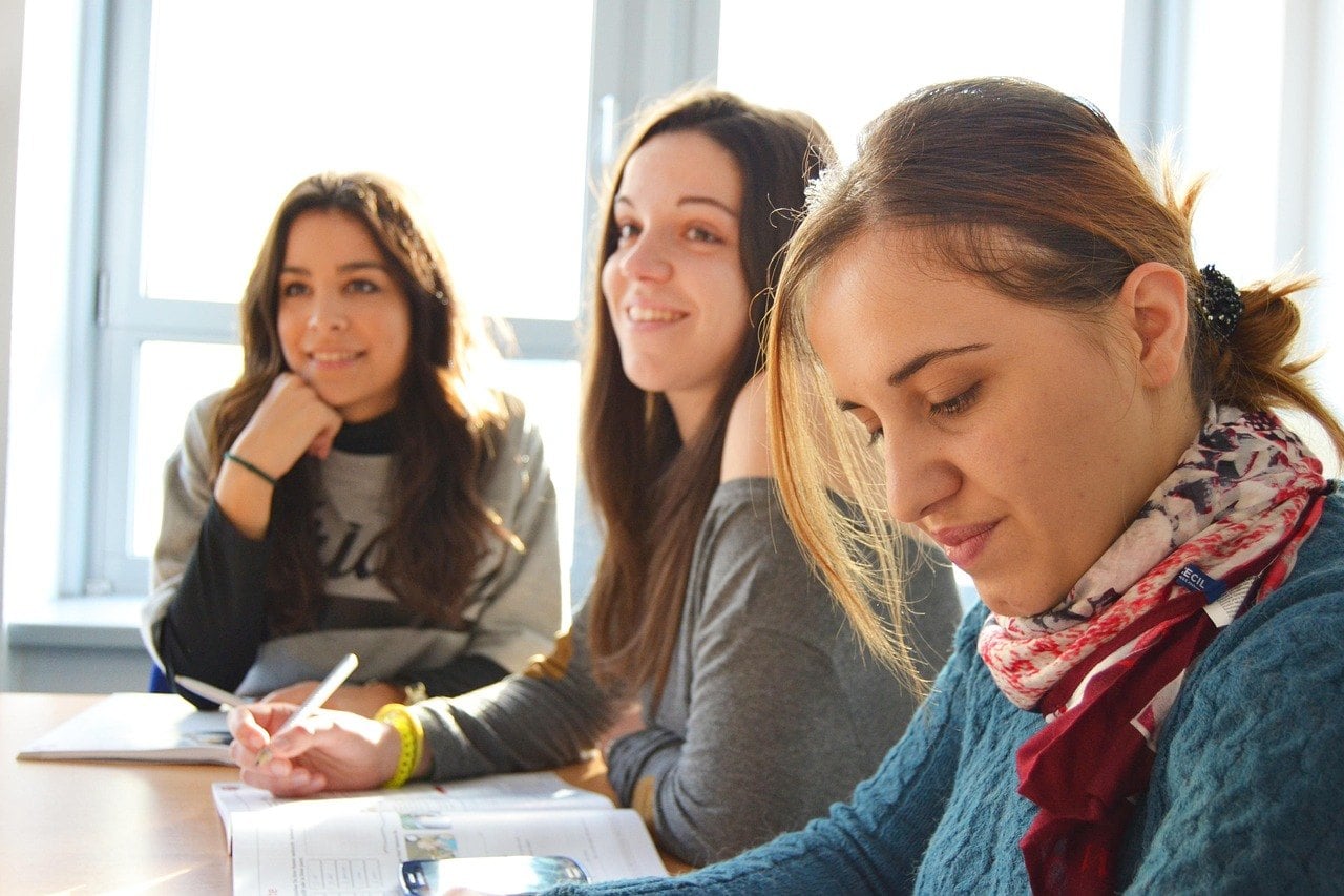 Drei Frauen sitzen an einem Tisch in einem hellen Raum und arbeiten mit Unterlagen