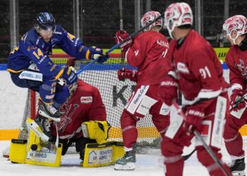 Spieler der Lausitzer Füchse im blauen Trikot bedrängt den Torhüter des EC Bad Nauheim vor dem Tor