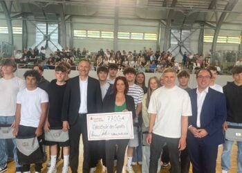 Sven Walter und Sandra Süßmuth halten einen Scheck über 7.700 Euro in der Sporthalle