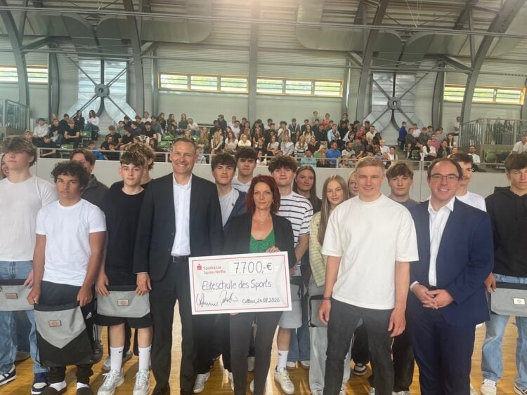 Sven Walter und Sandra Süßmuth halten einen Scheck über 7.700 Euro in der Sporthalle