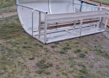 Umgekippter Spielerunterstand aus Metall und Kunststoff neben dem Sportplatz