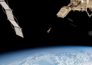 Drei CubeSats schweben vor der Erde, im Vordergrund ein Solarpaneel der Raumstation