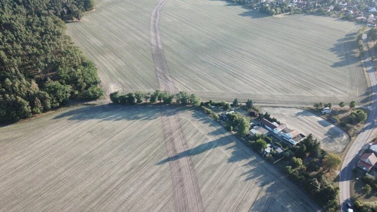 Luftbild: Die auf dem Feld markierte Trassenführung der geplanten Ortsumfahrung verläuft nahe an der Wohnbebauung