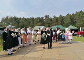 Menschen in sorbischer Tracht stehen bei einem Hochzeitszug auf einer Bühne im Freien
