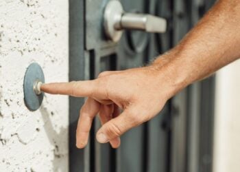 Hand klingelt an einer Haustür – Symbolbild zum Haustürbetrug