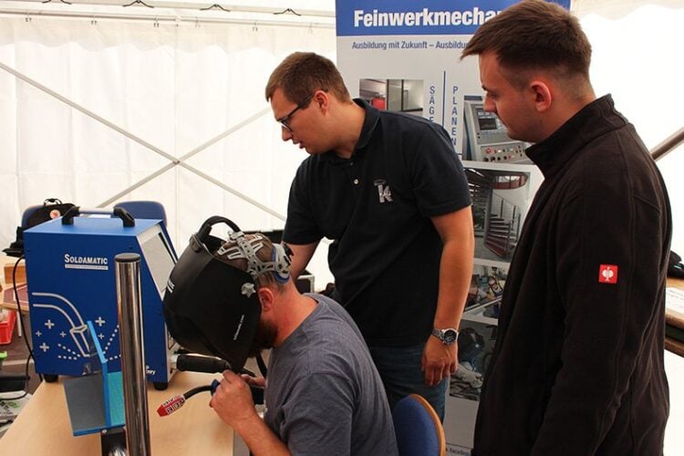 Jugendliche im Gespräch an einem Messestand der Ausbildungsmesse