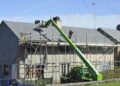 Wohnhaus mit Baugerüst, Handwerker arbeiten am Dach