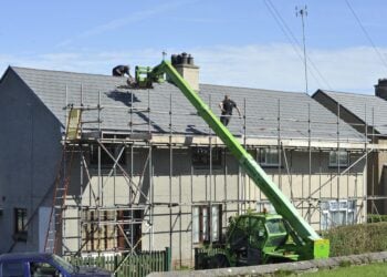 Wohnhaus mit Baugerüst, Handwerker arbeiten am Dach