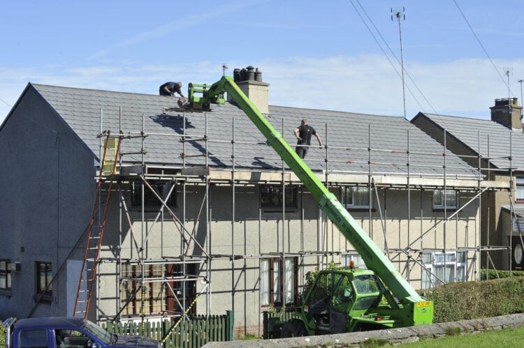 Wohnhaus mit Baugerüst, Handwerker arbeiten am Dach