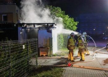 Einsatzkräfte löschen mit einem Wasserstrahl den brennenden Carport