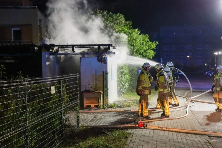 Einsatzkräfte löschen mit einem Wasserstrahl den brennenden Carport