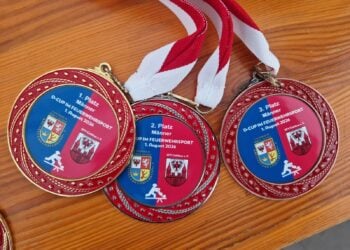 Drei Medaillen des D-Cups im Feuerwehrsport liegen auf einem Tisch