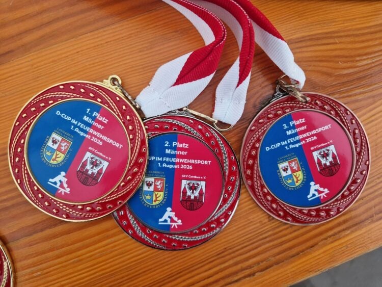 Drei Medaillen des D-Cups im Feuerwehrsport liegen auf einem Tisch