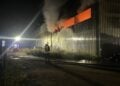 Feuerwehrleute vor dem geöffneten Hallentor der Recyclingfirma