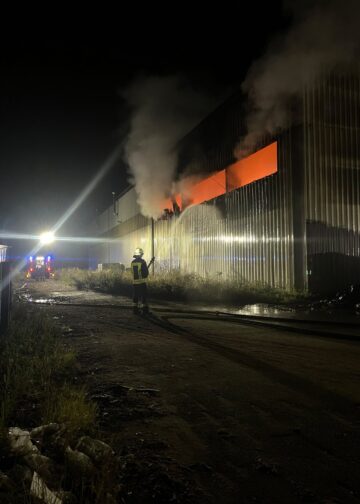 Feuerwehrleute vor dem geöffneten Hallentor der Recyclingfirma