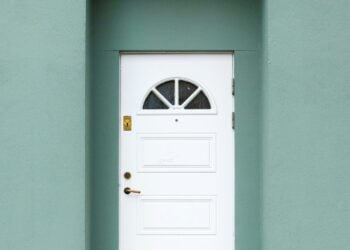 Weiße Haustür mit Oberlicht in einer grün gestrichenen Hausfassade