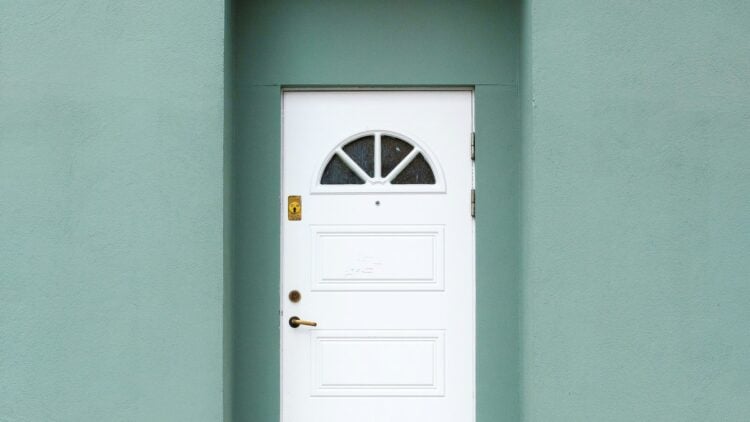 Weiße Haustür mit Oberlicht in einer grün gestrichenen Hausfassade