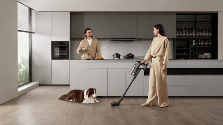 Person saugt mit einem kabellosen Staubsauger Krümel vom Küchenboden