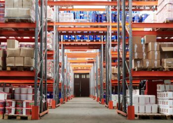 Weitwinkelansicht einer Logistikhalle mit gefüllten Hochregalen und Kartons