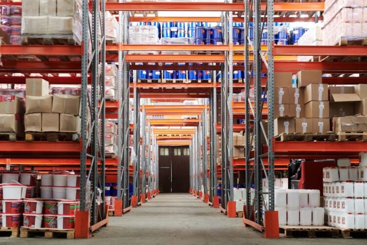 Weitwinkelansicht einer Logistikhalle mit gefüllten Hochregalen und Kartons