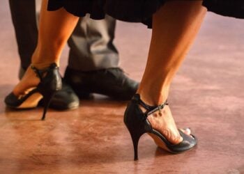 Nahaufnahme der Füße eines Tanzpaares in schwarzen Tanzschuhen mit Absatz und Riemchen auf einer Tanzfläche