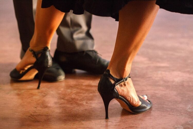 Nahaufnahme der Füße eines Tanzpaares in schwarzen Tanzschuhen mit Absatz und Riemchen auf einer Tanzfläche