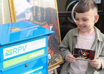 Ein Junge hält eine bemalte Gondula-Postkarte vor einem blauen RPV-Briefkasten