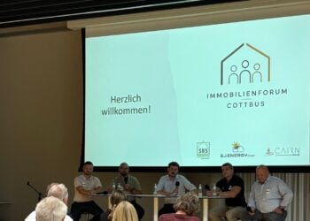 Fünf Männer sitzen auf einem Podium vor einer Leinwand mit dem Schriftzug Immobilienforum Cottbus