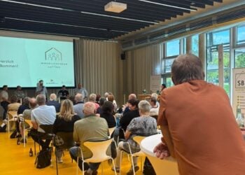Blick von hinten in einen Saal mit Publikum, vorn eine Leinwand mit dem Logo des Immobilienforums