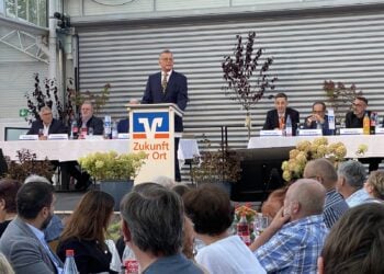 Redner am Pult mit Volksbank-Logo vor dem Präsidium, davor sitzende Mitglieder
