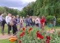 Tagungsteilnehmer stehen bei einer Führung vor einem Blumenbeet im Park