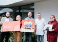 Fünf Personen mit Spendenscheck und einem selbst gebauten Puppentheater vor dem Kinderhaus