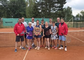 Tennisspielerinnen und -spieler stehen mit Schlägern vor dem Netz auf dem Sandplatz