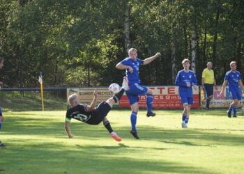 Spieler in Blau nimmt den Ball in der Luft an, Gegenspieler am Boden
