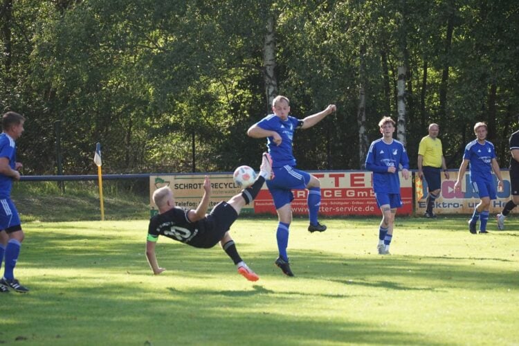 Spieler in Blau nimmt den Ball in der Luft an, Gegenspieler am Boden