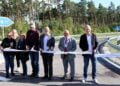 Sieben Personen durchschneiden ein Band auf der neuen Auffahrt zur A117, im Hintergrund Kiefernwald