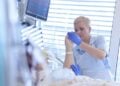 Physiotherapeutin bewegt die Hand einer Patientin auf der Intensivstation