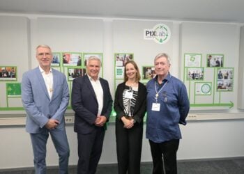 Vier Personen stehen nebeneinander vor einer Wand mit Fotos und dem Logo des PtX Lab Lausitz