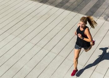 Läuferin in roten Laufschuhen beim Training auf gepflastertem Weg