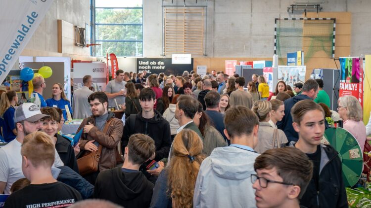 Jugendliche zwischen den Ständen der Ausbildungsmesse in der Turnhalle des Oberstufenzentrums