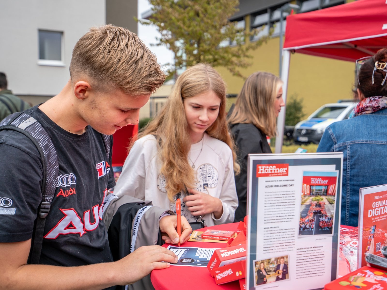 Zwei Jugendliche füllen an einem Messestand einen Bogen aus
