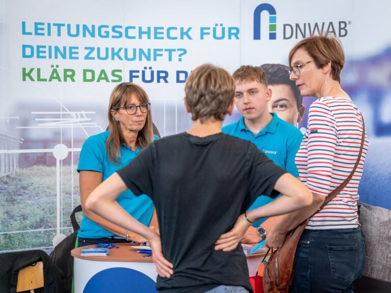 Zwei Mitarbeiter eines Versorgers im Gespräch mit Besuchern