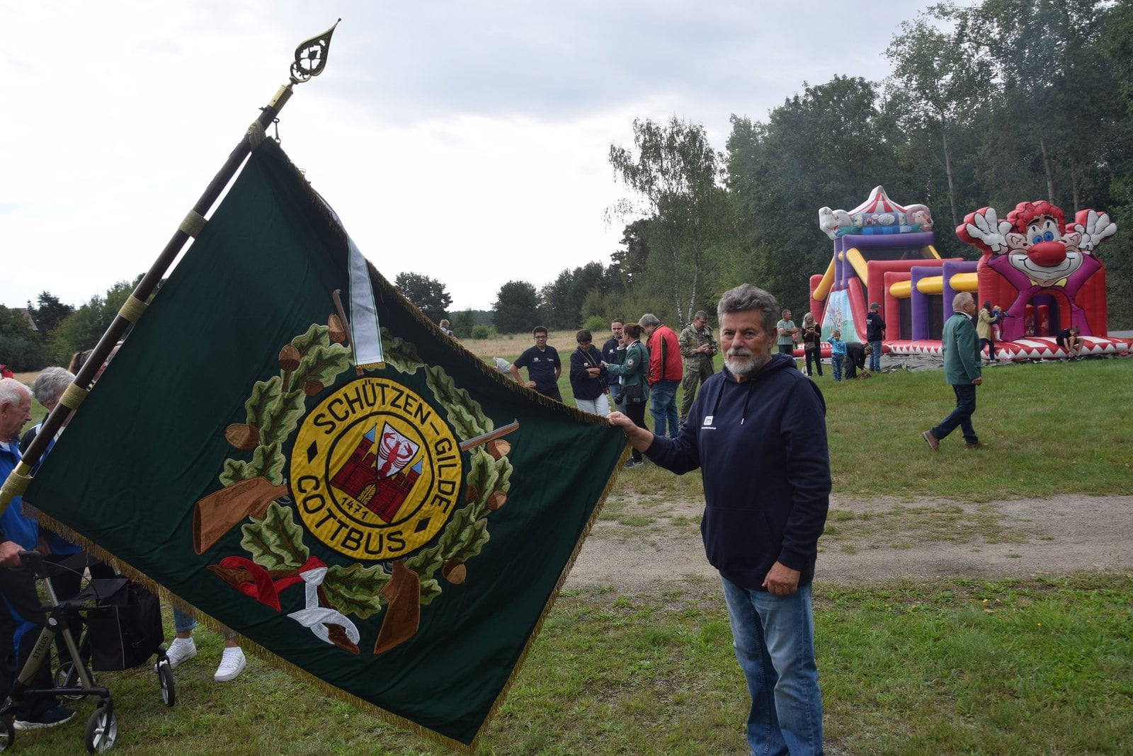 Mann hält die Fahne der Schützengilde Cottbus auf einer Wiese