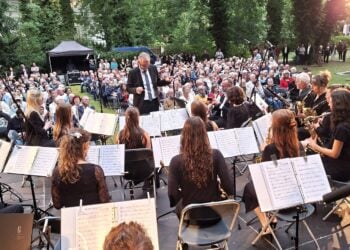 Blasorchester mit Dirigent bei einem Konzert vor Publikum im Freien
