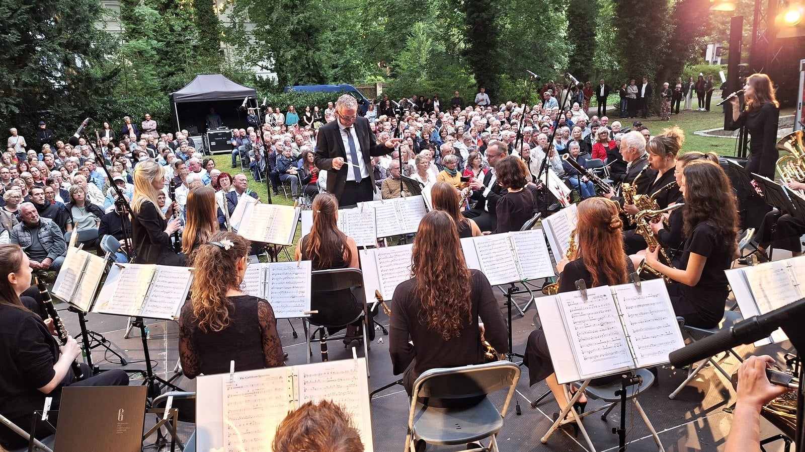 Blasorchester mit Dirigent bei einem Konzert vor Publikum im Freien