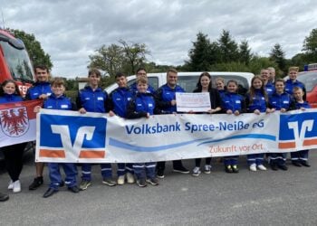 Jugendfeuerwehr Trebendorf mit Spendenscheck vor einem Feuerwehrfahrzeug
