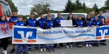 Jugendfeuerwehr Trebendorf mit Spendenscheck vor einem Feuerwehrfahrzeug