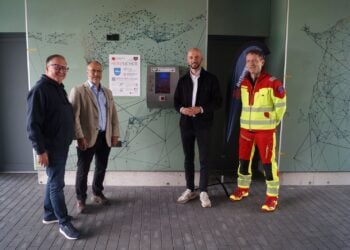 Drei Männer nehmen einen Defibrillator am Spreewald Stadion in Betrieb